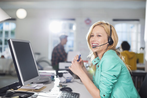 Businesswoman talking on headset at desk